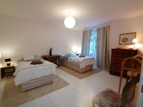 une chambre avec deux lits et une commode et une fenêtre dans l'établissement Les Vignes du Château Duras Wifi et Belle vue, à Duras