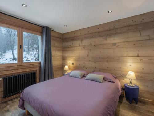 une chambre avec un lit et un mur en bois dans l'établissement Chalet Jeane proche du Centre ville de Megève, à Megève