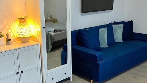 a blue couch in a room with a mirror at Oázis Apartmanház Balatonalmádi in Balatonalmádi