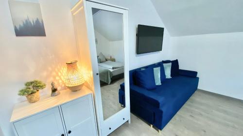 a living room with a blue couch and a mirror at Oázis Apartmanház Balatonalmádi in Balatonalmádi