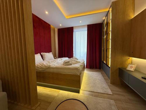 a bedroom with a bed in a room with red curtains at Fashion Residence Hill in Kopaonik