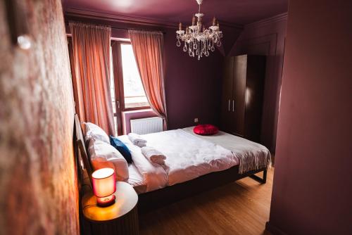 a bedroom with a bed and a chandelier at The Vardo: Elegant Villa in Predelut in Bran