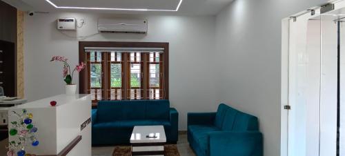 a living room with two blue chairs and a table at Palm Tree Haven in Bhubaneshwar