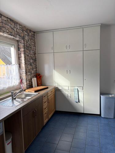 a kitchen with white cabinets and a sink and a window at Ferienwohnung Aurach in Aurach