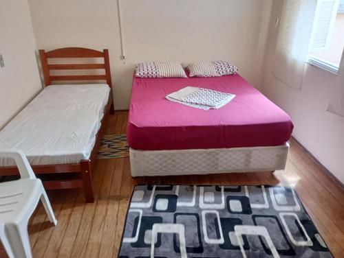 a bedroom with two beds and a chair and a rug at Hostel Baladi in Socorro
