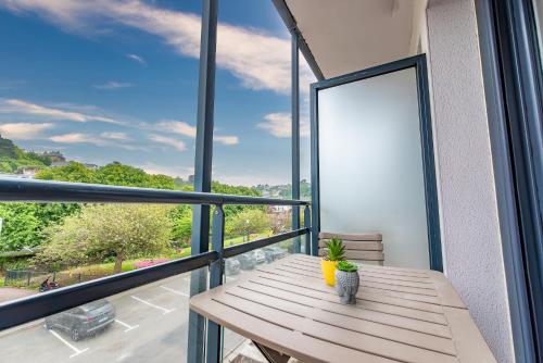 d'une table en bois sur un balcon avec une grande fenêtre. dans l'établissement APPARTEMENT AU PIED DE LA PLAGE trestraou, à Perros-Guirec