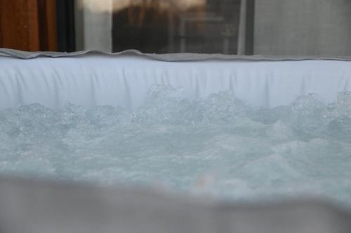 a tub filled with icy water next to a window at Pinéa Lodge - Chalet Authentique en Pin des Landes in Saint-Yaguen
