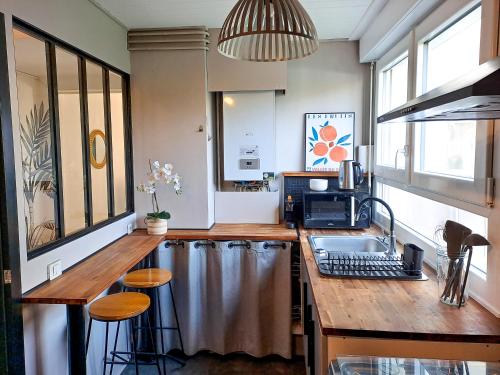 une cuisine avec un évier et un comptoir avec des tabourets dans l'établissement Vannes - L'étoilé, parking et linge inclus, à Vannes