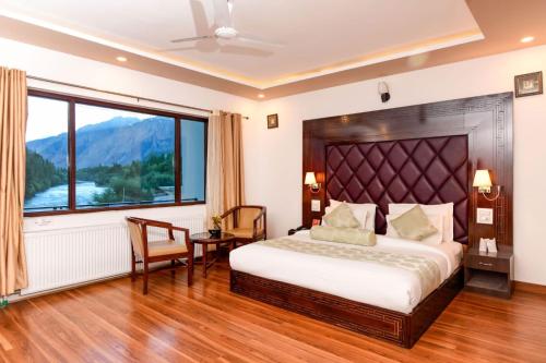 a bedroom with a bed and a large window at Hotel Chhutuk Heights in Kargil