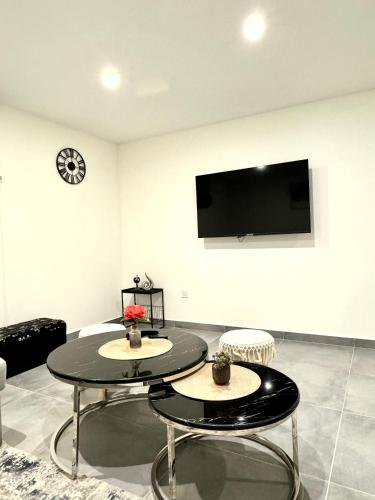 - un salon avec deux tables et une télévision à écran plat dans l'établissement Duplex chaleureux, à Livry-Gargan
