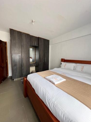 KerichoにあるComfort2 bedrooms in kericho townのベッドルーム1室(大型ベッド1台、木製キャビネット付)