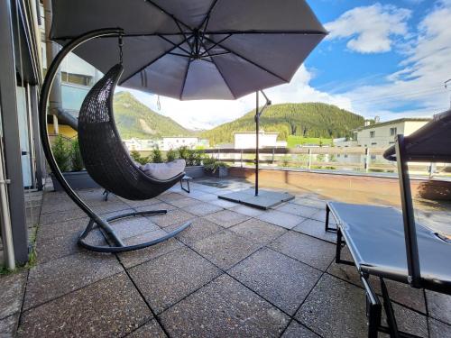 a patio with a hammock and an umbrella at Für 4 Pers neben Talstation Parsennbahn und Bünda-Lift mit privater Dachterrasse 10min walk to WEF in Davos