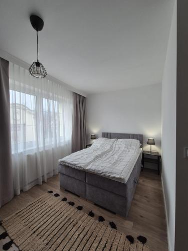 a white bedroom with a bed and a large window at Pokoje pod Kamienną Bramą in Chojnice