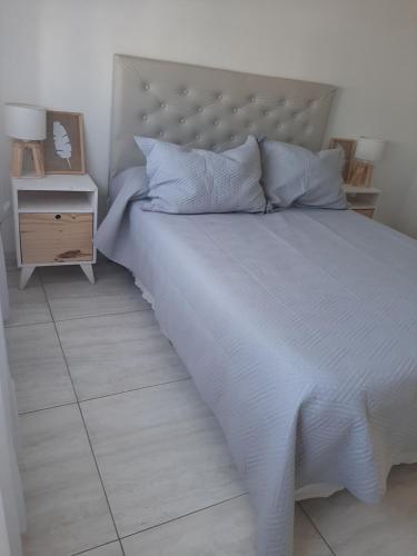 a bed with a white bedspread and a night stand at Ayres Apart in Chivilcoy