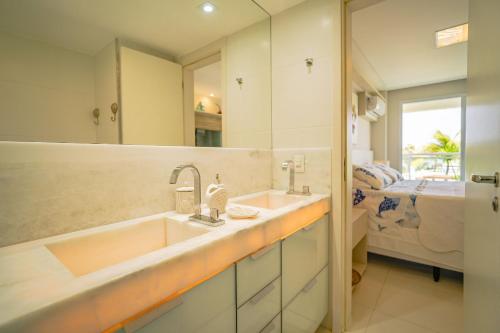 une salle de bain avec un lavabo, un miroir et un lit dans l'établissement In Mare Bali Resort com Vista Mar by Qavi, à Parnamirim