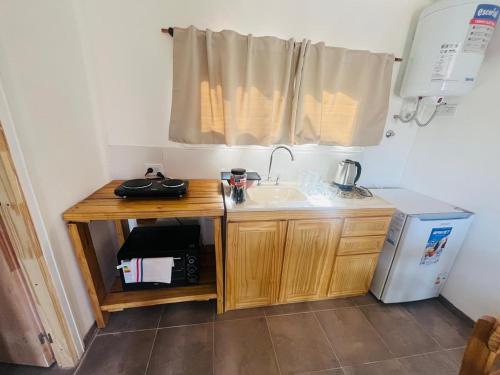 a small kitchen with a sink and a refrigerator at Cabañas Boutique La Soñada in Fiambala