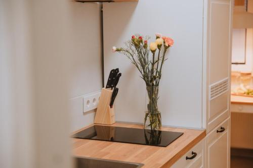 a vase with flowers on a counter in a kitchen at Apartman Esseg - Luxury Living in Historic Esseg - SELF CHECK IN in Osijek