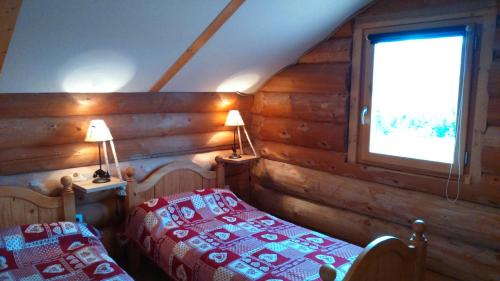une chambre avec deux lits dans une cabane en rondins dans l'établissement les fustes caturiges, à Chorges