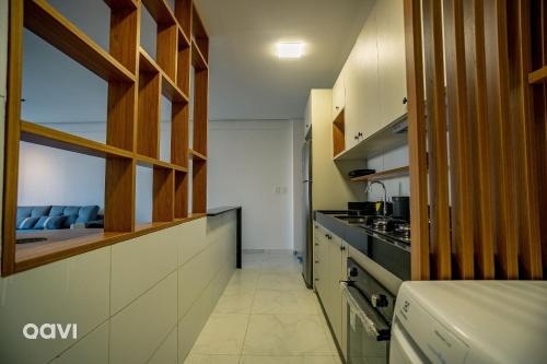 a kitchen with white counters and wooden cabinets at Flats Confortáveis em Manaíra Mindset - Qavi in Tambaú