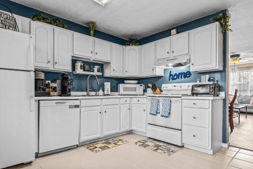 a white kitchen with blue walls and white appliances at Woodstone Retreat Condo right next to UGA golf course 2475 in Athens
