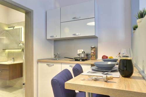 a kitchen with a table with purple chairs and a wine glass at D&A Center Apartments with FREE Parking in Pula