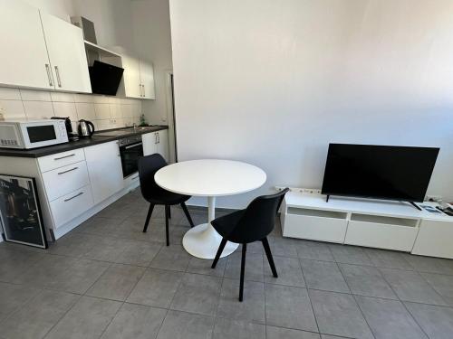 a kitchen with a white table and chairs and a tv at 2-Zimmer Wohnung Würzburger Straße - Innenstadtlage Aschaffenburg in Aschaffenburg