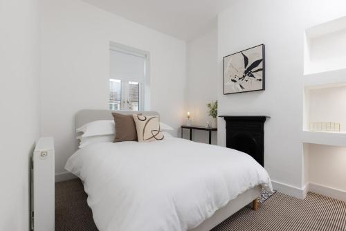 a white bedroom with a bed and a fireplace at 5 Stockland Street in Caerphilly