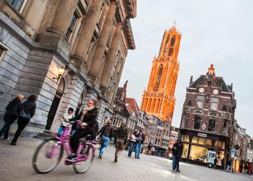 people walking down a street with a clock tower at Stayokay Hostel Utrecht Centrum in Utrecht