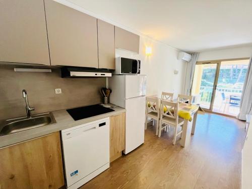 Il comprend une cuisine équipée d'un réfrigérateur blanc et d'une table avec des chaises. dans l'établissement Le vallon du Roi, à Sanary-sur-Mer