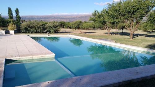 a swimming pool with blue water and trees in the background at Las Icarias Casas de campo in Las Calles