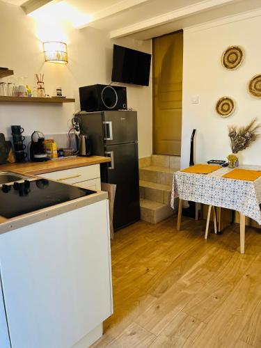 Il comprend une cuisine équipée d'une table et d'un réfrigérateur noir. dans l'établissement Appartement avec terrasse arborée proche LOURMARIN, à Cadenet