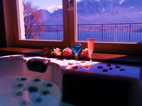 a bath tub with two wine glasses and a window at Residence Le Azalee & SPA in Vercana
