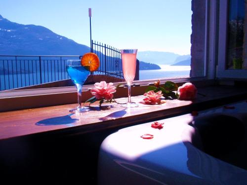 a table with two glasses and flowers on a balcony at Residence Le Azalee & SPA in Vercana