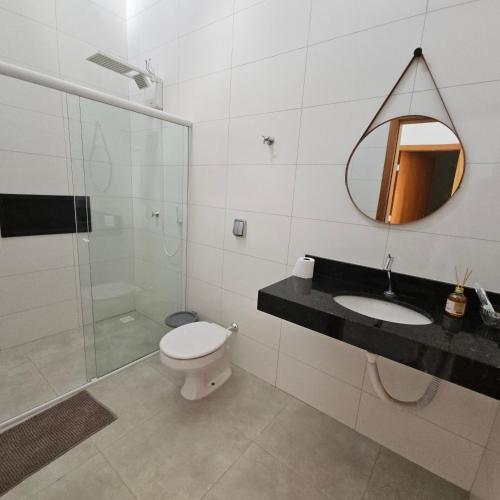 a bathroom with a toilet and a sink and a mirror at Casa Nova 01 in Primavera do Leste