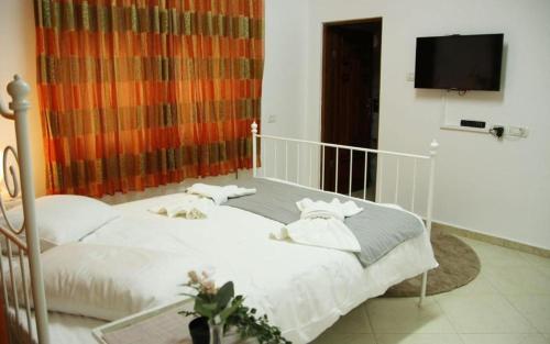 a bedroom with a white bed and a flat screen tv at אחוזות החרמון in Mas'ade
