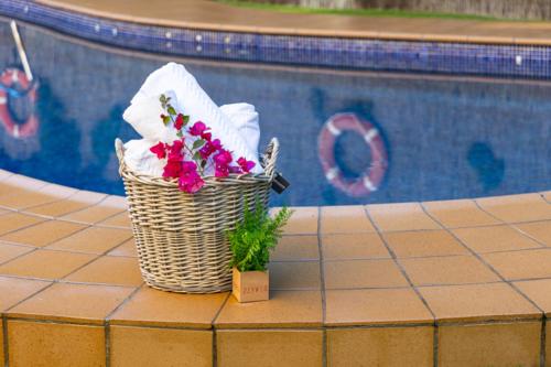 a basket of towels and flowers next to a pool at Hotel Plaza Del Castillo in Málaga