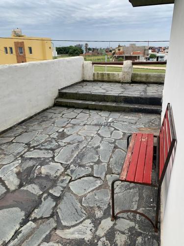 a red bench sitting on top of a stone patio at Casa Bereber in Santa Clara del Mar