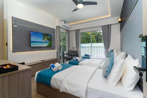 two beds in a hotel room with a tv at Madi Maldives Ukulhas in Ukulhas