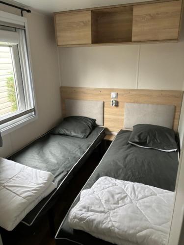 deux lits dans une petite pièce avec une fenêtre dans l'établissement Amira 6-8 personnes, à Saint-Jean-de-Monts
