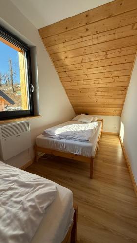 two beds in a room with a window at Domki Wilcza C in Wilcza