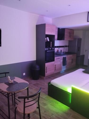 Cette chambre comprend un lit, une table et une cuisine. dans l'établissement Logement au coeur de saint omer, à Saint-Omer