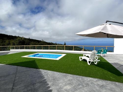 a patio with an umbrella and chairs and a pool at Apartamento de ensueño, vistas al bosque, Stevier in Icod de los Vinos