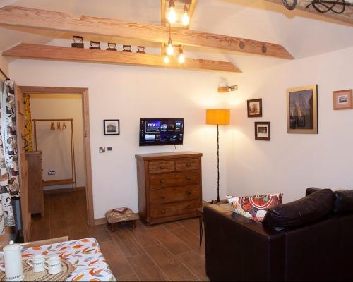 a living room with a couch and a flat screen tv at The Old Stables in Heathfield