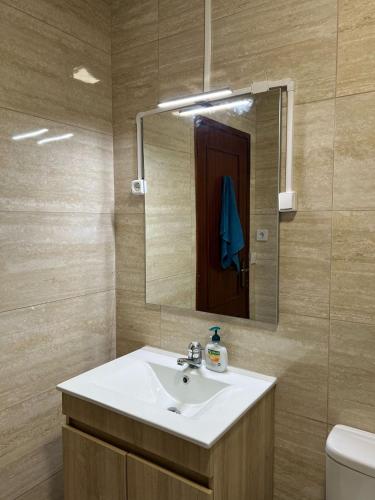 a bathroom with a sink and a mirror and a toilet at Lovely 2 bedroom apartment 100m from the beach in Vila do Conde