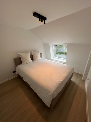 a bedroom with a large white bed with a window at Maison Ter Wallen in Izegem