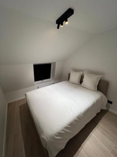 a bedroom with a large white bed with a flat screen tv at Maison Ter Wallen in Izegem