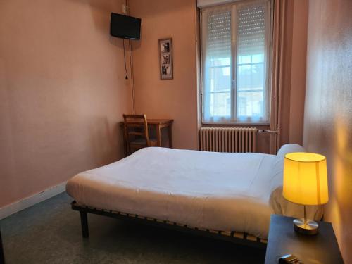 a bedroom with a bed and a lamp and a window at Hôtel de Vendée Restaurant Les2M in Fontenay-le-Comte