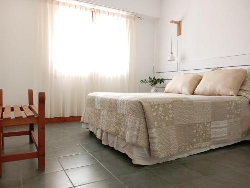 um quarto com uma cama, uma cadeira e uma janela em Socaire, tu refugio en Chascomús em Chascomús