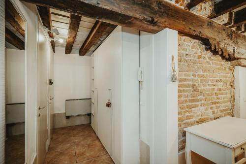 una camera con pareti bianche e un muro di mattoni di Autentico rifugio veneziano Bilocale nel cuore di Cannaregio a Venezia