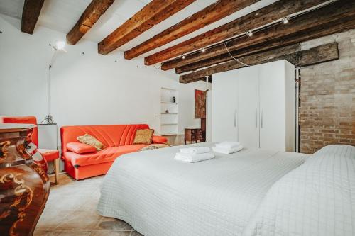 una camera con un letto bianco e un divano rosso di Autentico rifugio veneziano Bilocale nel cuore di Cannaregio a Venezia